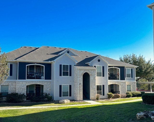 a large white house with a yard and a blue sky