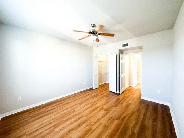 an empty living room with a ceiling fan and wood floors
