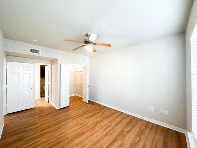an empty living room with a ceiling fan and wood floors