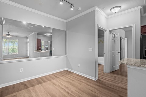 A spacious room with wooden flooring and white walls.