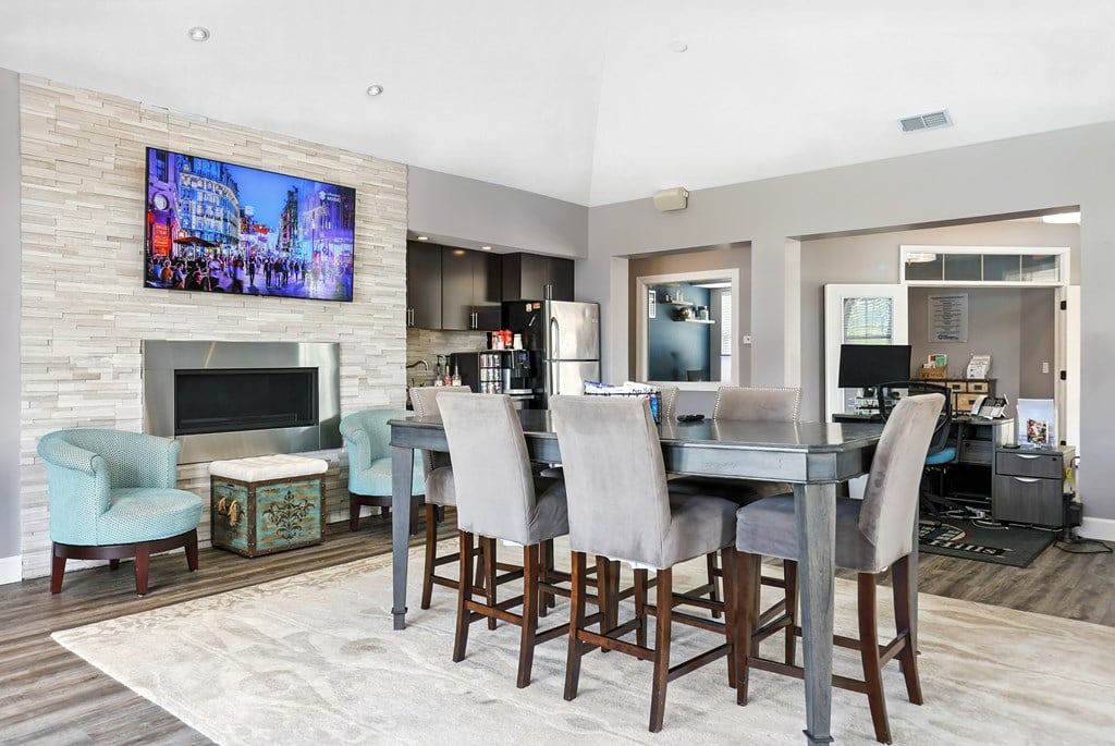 A modern dining room with a large TV mounted above the fireplace at Bramblett Hills Luxury Apartments in O Fallon MO 63366