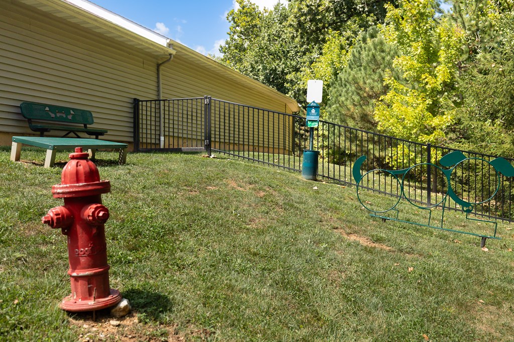A red fire hydrant is in the foreground of a grassy area at Bramblett Hills Luxury Apartments in O Fallon MO 63366