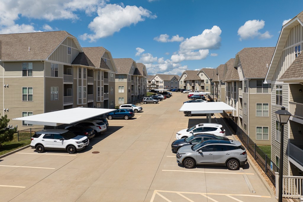 A parking lot with cars and apartment buildings in the background at Bramblett Hills Luxury Apartments in O Fallon MO 63366