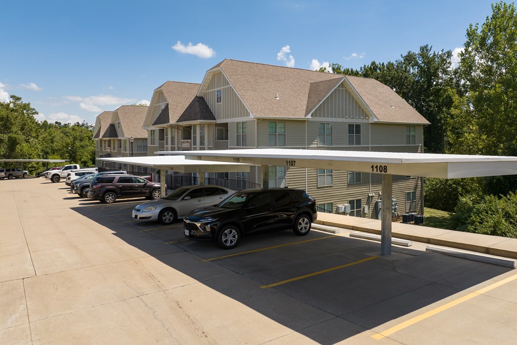 A carport in a parking lot in front of a building  at Bramblett Hills Luxury Apartments in O Fallon MO 63366