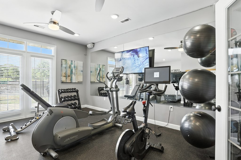 A home gym with a treadmill, exercise bike, and other equipment at Bramblett Hills Luxury Apartments in O Fallon MO 63366