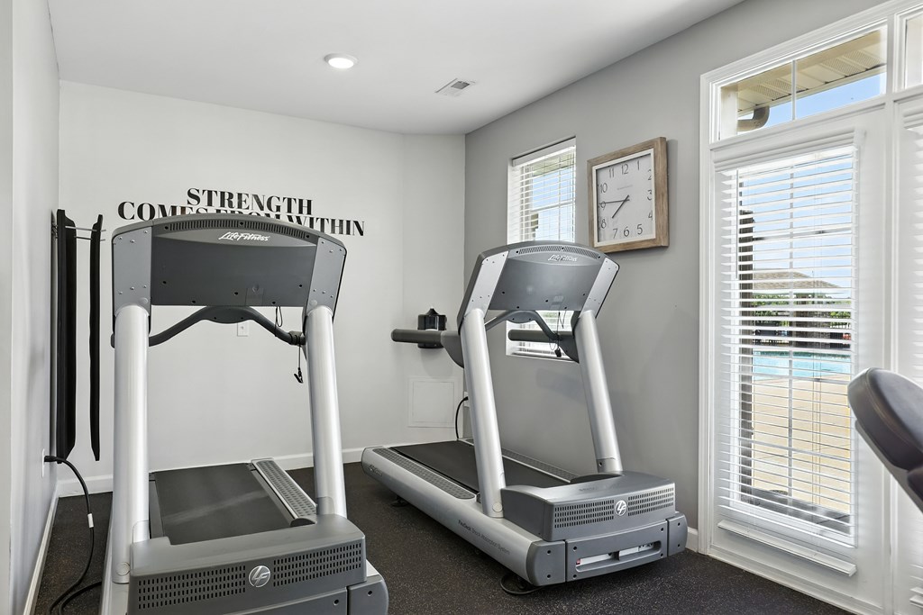 Two treadmills are placed in a room with a wall that says