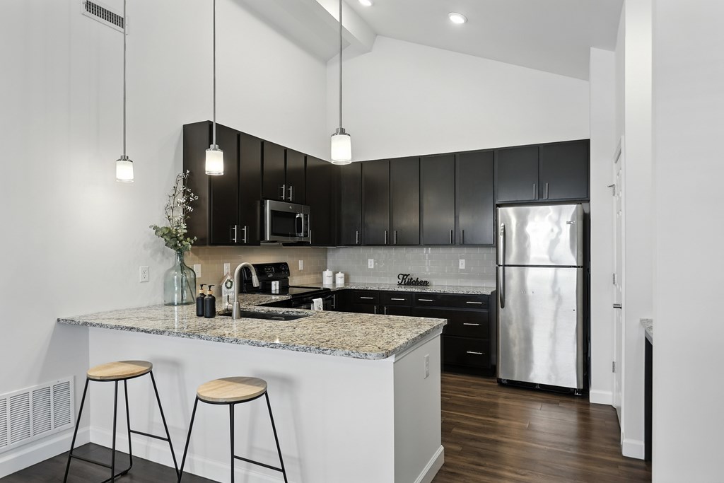 A kitchen with black cabinets and a granite countertop at Bramblett Hills Luxury Apartments in O Fallon MO 63366