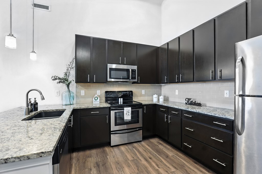 A kitchen with black cabinets and a stainless steel refrigerator at Bramblett Hills Luxury Apartments in O Fallon MO 63366