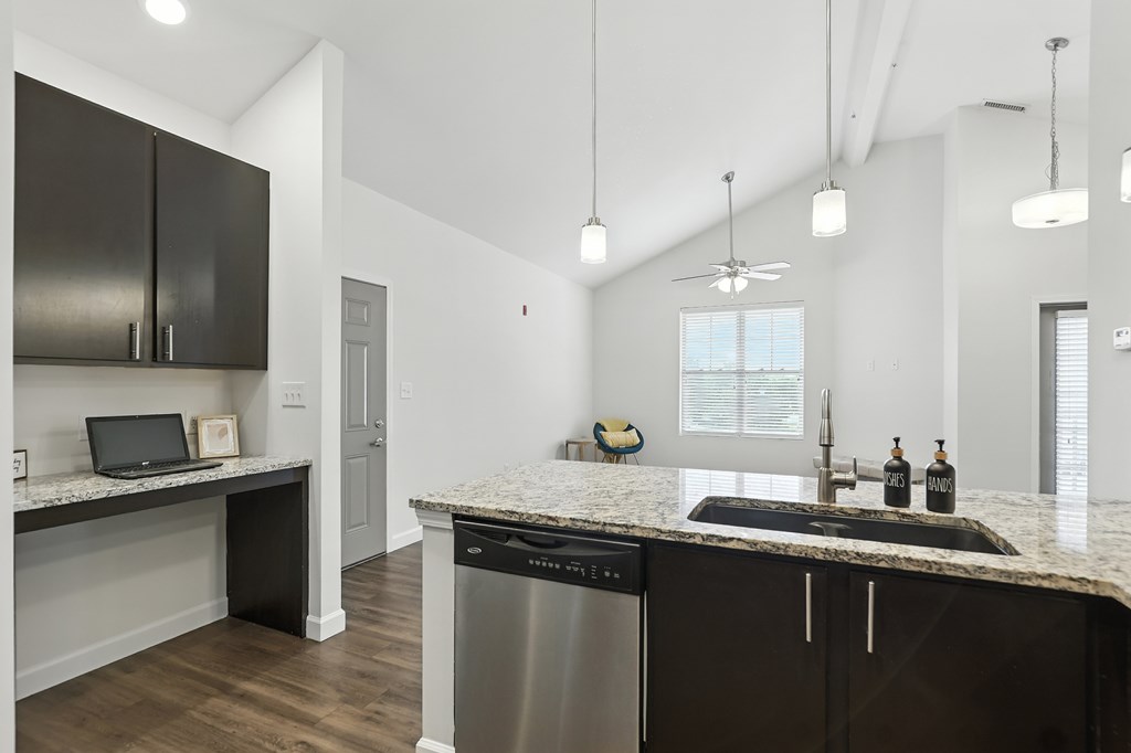 A modern kitchen with dark brown cabinets and a granite countertop at Bramblett Hills Luxury Apartments in O Fallon MO 63366