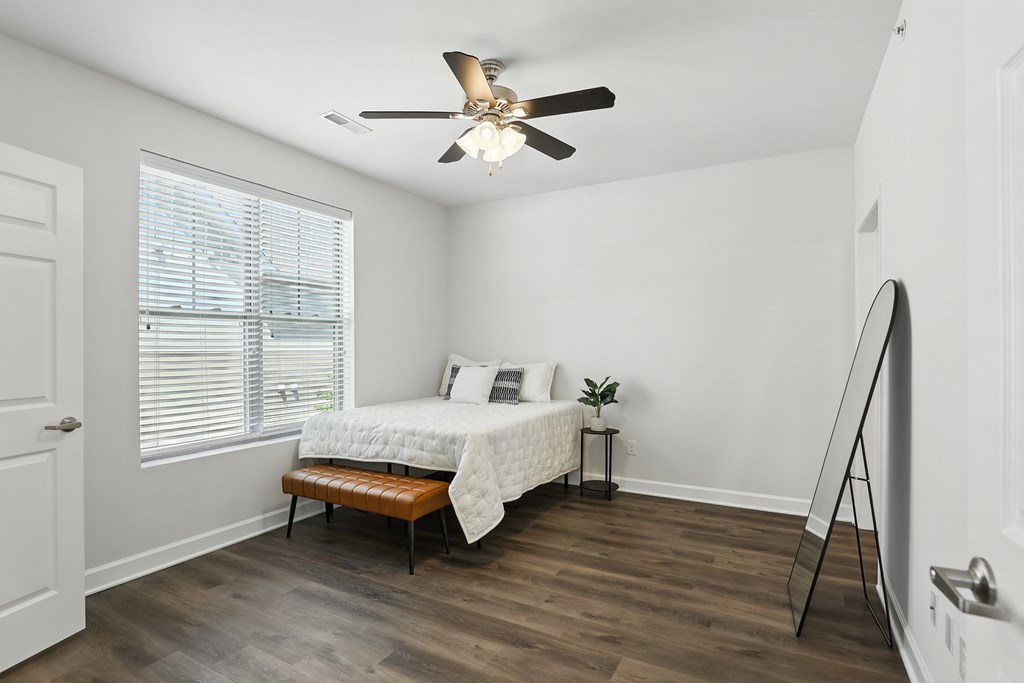 A bedroom with a bed, bench, and a ceiling fan at Bramblett Hills Luxury Apartments in O Fallon MO 63366