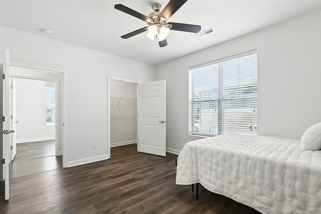 A bedroom with a bed, dresser, and mirror at Bramblett Hills Luxury Apartments in O Fallon MO 63366