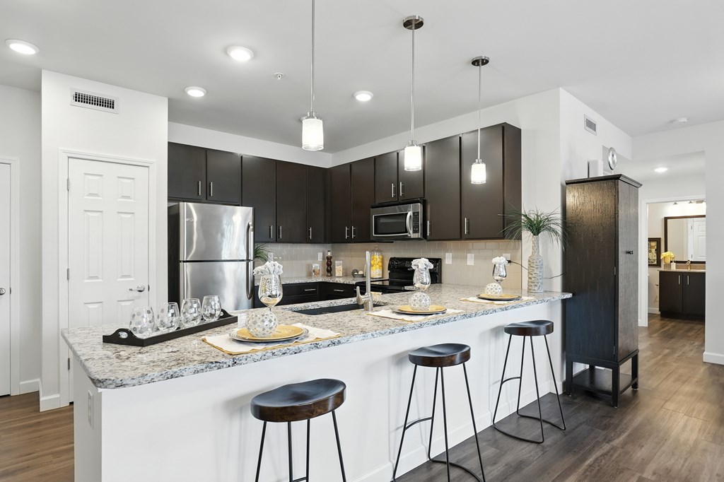 A modern kitchen with a bar area and stools at Bramblett Hills Luxury Apartments in O Fallon MO 63366