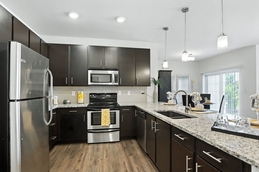 A modern kitchen with a stainless steel refrigerator and black cabinets  at Bramblett Hills Luxury Apartments in O Fallon MO 63366