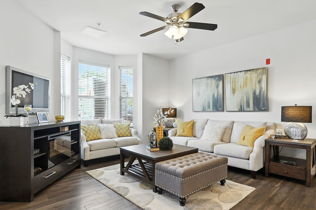 A living room with a white couch, a coffee table, and a ceiling fan at Bramblett Hills Luxury Apartments in O Fallon MO 63366
