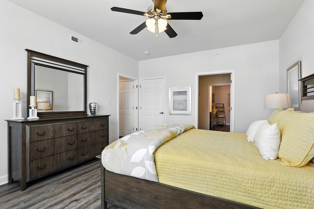 A bedroom with a bed, dresser, and mirror at Bramblett Hills Luxury Apartments in O Fallon MO 63366