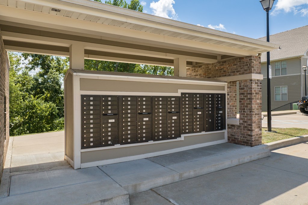 A row of mailboxes are on the sidewalk under a covered area at Bramblett Hills Luxury Apartments in O Fallon MO 63366