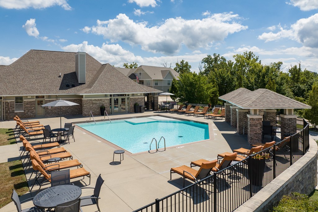A pool surrounded by chairs and a stone wall at Bramblett Hills Luxury Apartments in O Fallon MO 63366