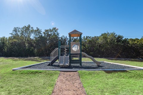 A playground with a slide and a clock tower.