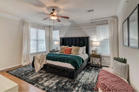 A bedroom with a large bed and a ceiling fan.