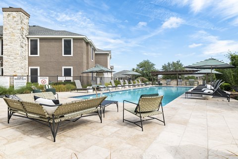 A pool area with two lounge chairs and a building in the background.