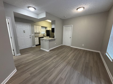 A kitchen with a countertop and cabinets is visible through a doorway.