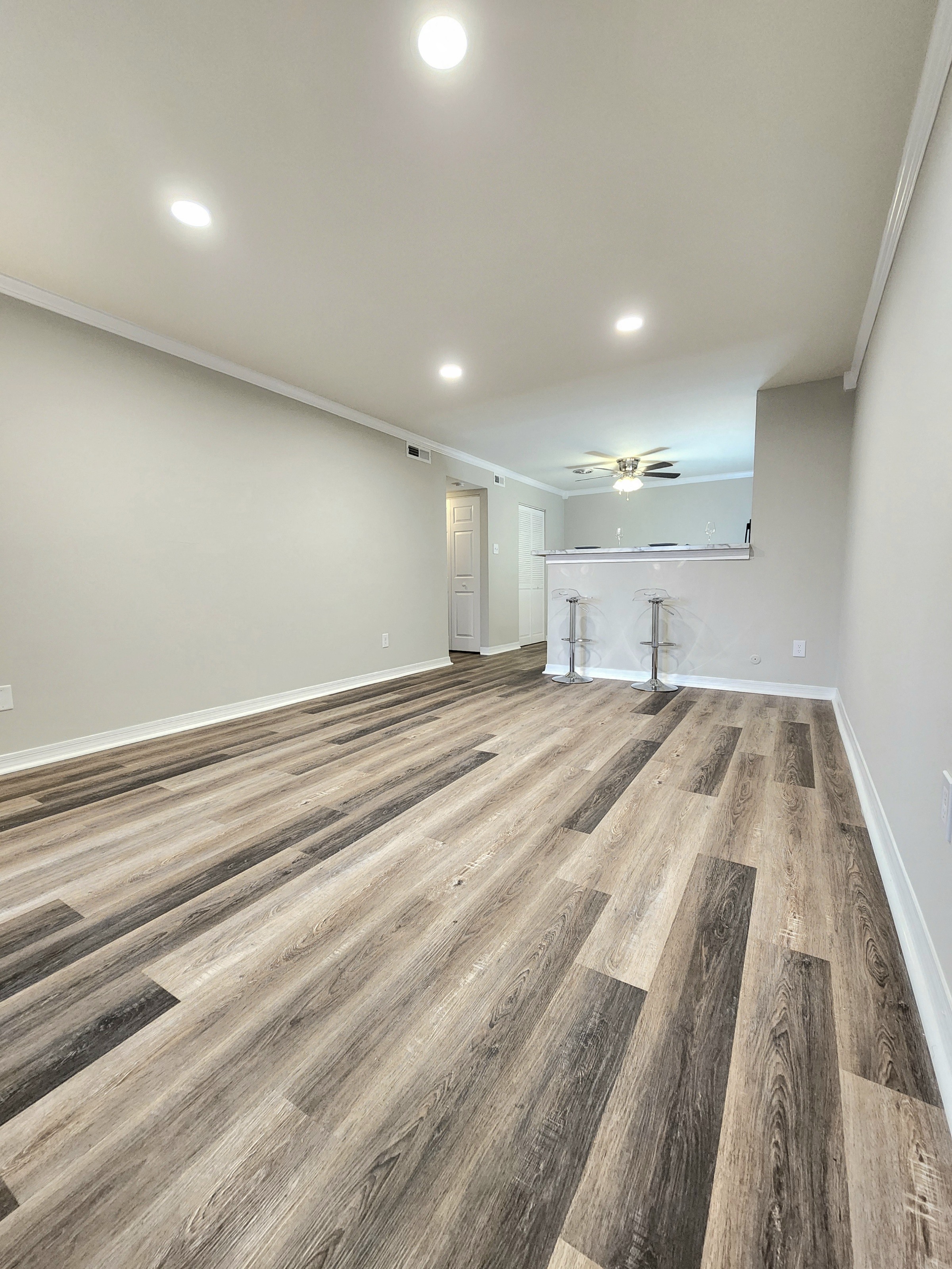 an empty living room with wood flooring and a ceiling fan