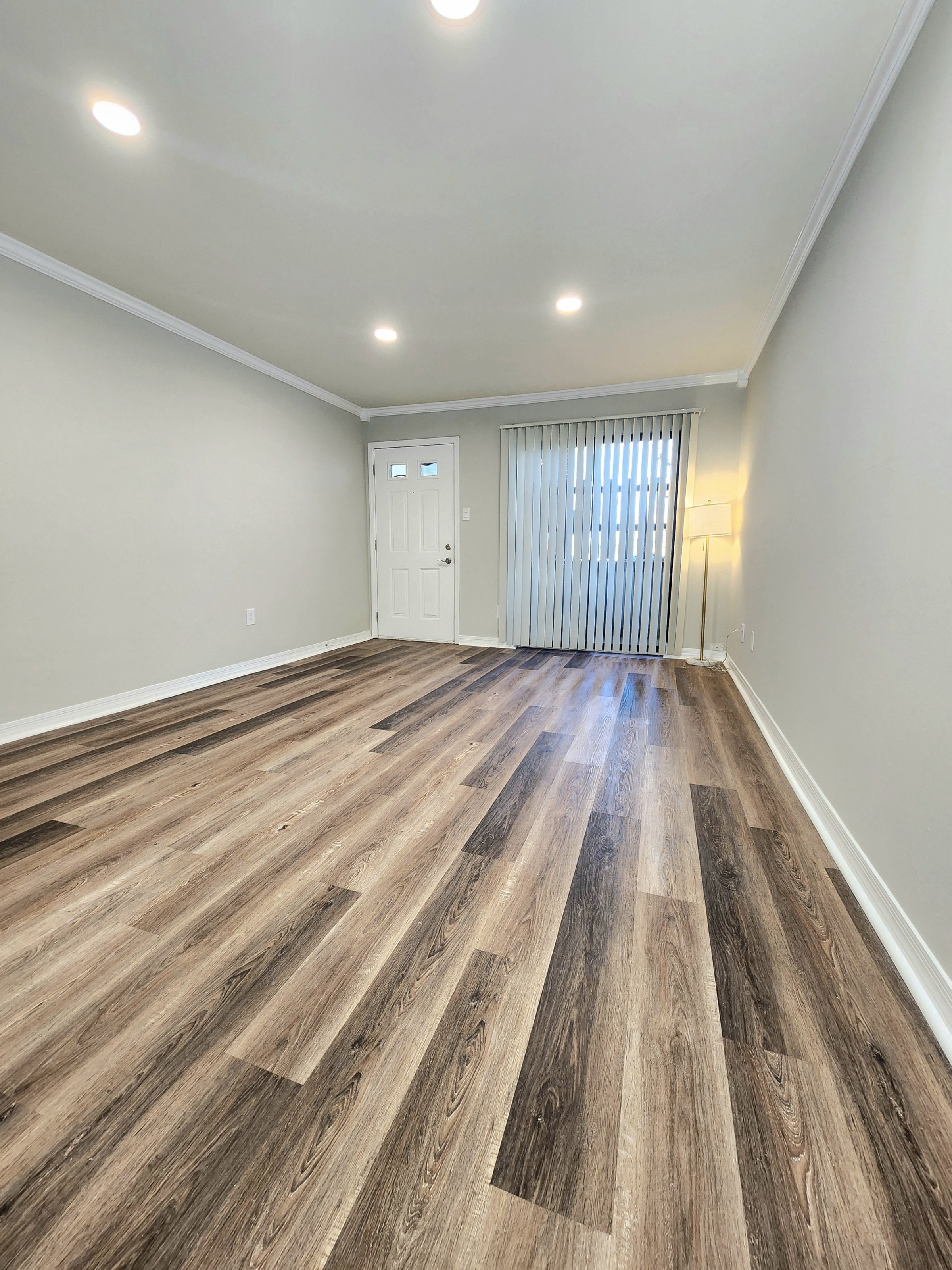 a living room with hardwood flooring and a door to a bedroom