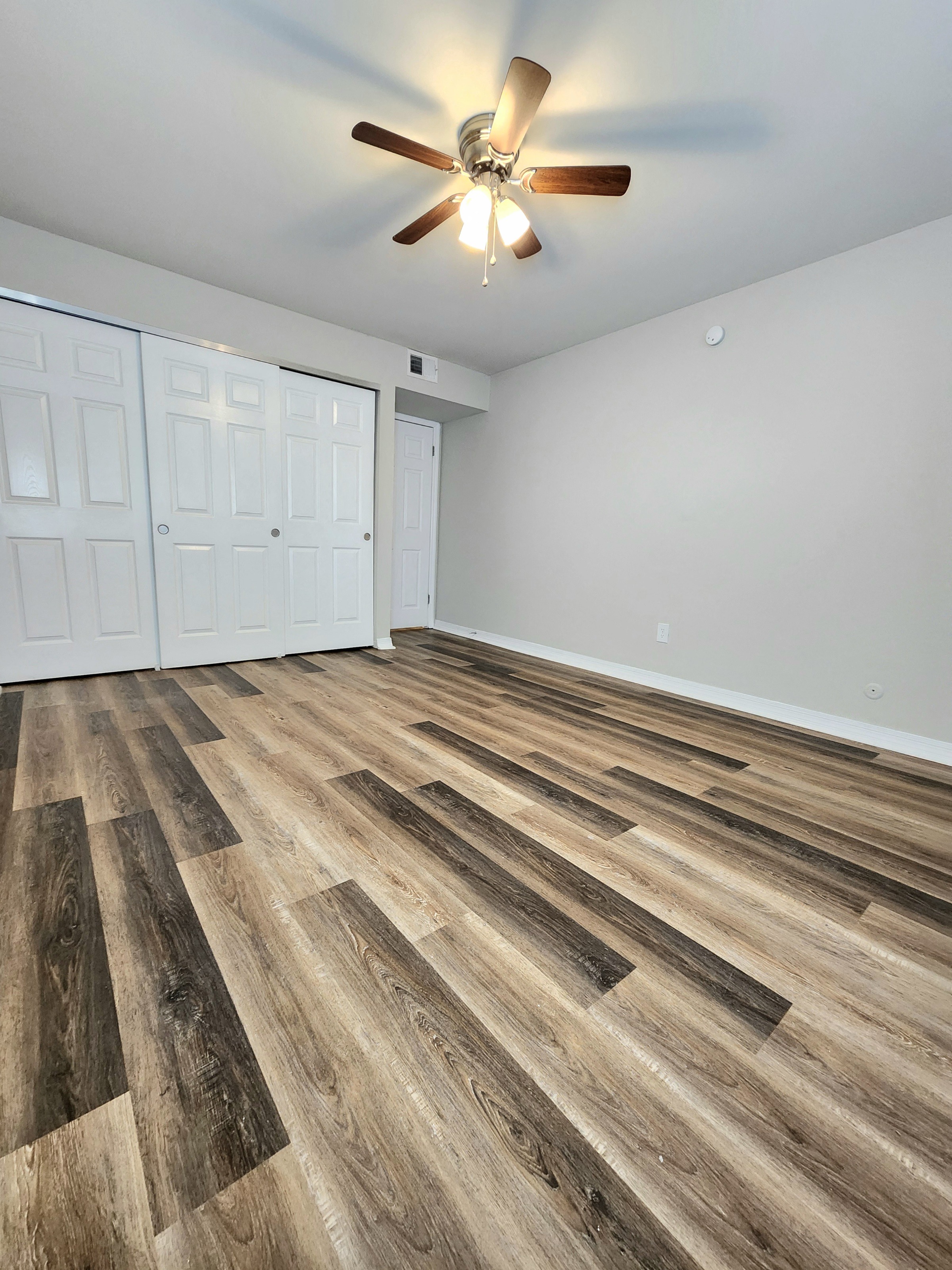a living room with wood flooring and a ceiling fan