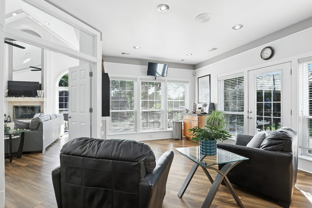 A living room with a black chair and a glass coffee table.