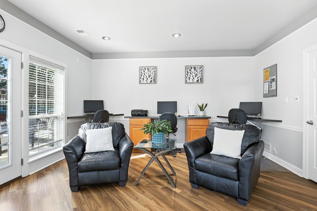 Two black leather chairs are placed in a living room with a wooden floor.