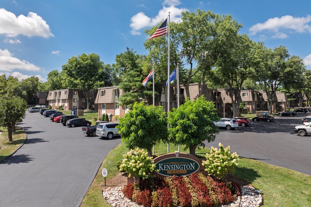 A street view of Kensington with cars parked on the side and trees lining the road.