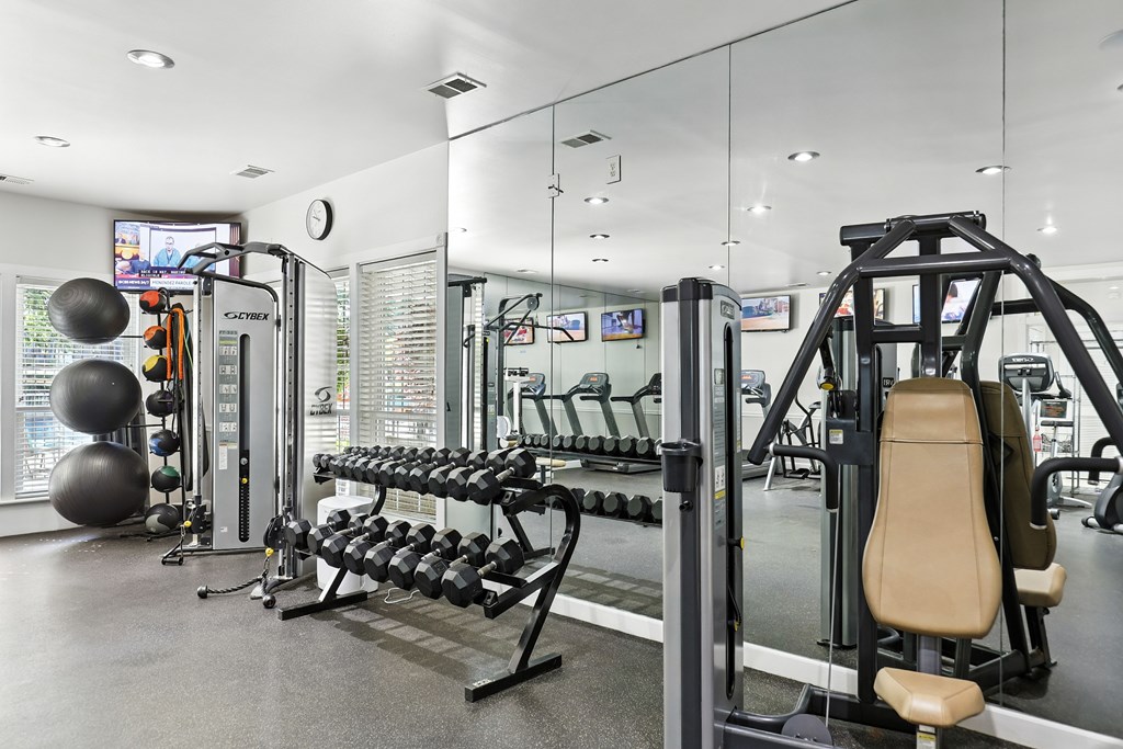 A gym with a variety of equipment including a leg press machine, a cable machine, and a squat rack.