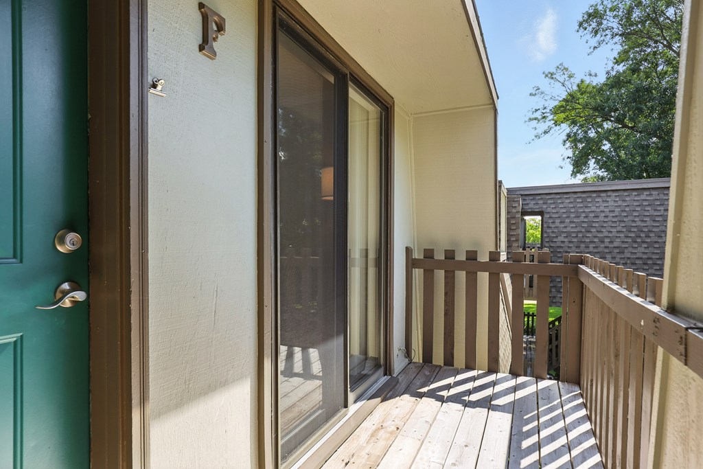 A green door with a glass window and a wooden deck.