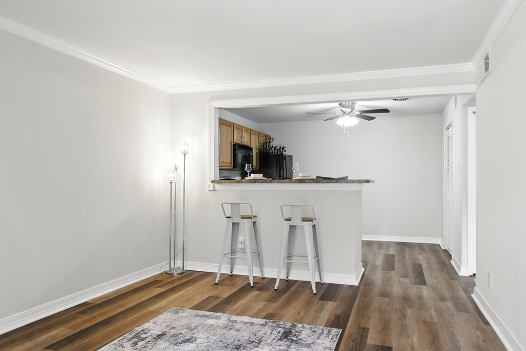 A kitchen with white walls and wooden floors with a bar area.