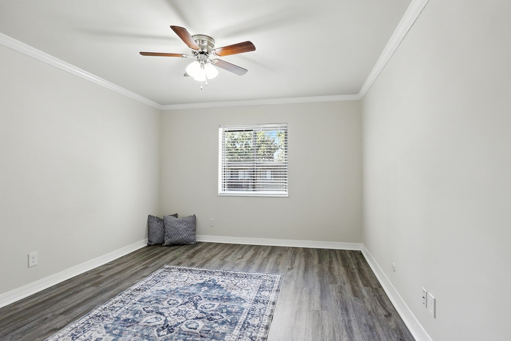 A room with a ceiling fan and a rug on the floor.