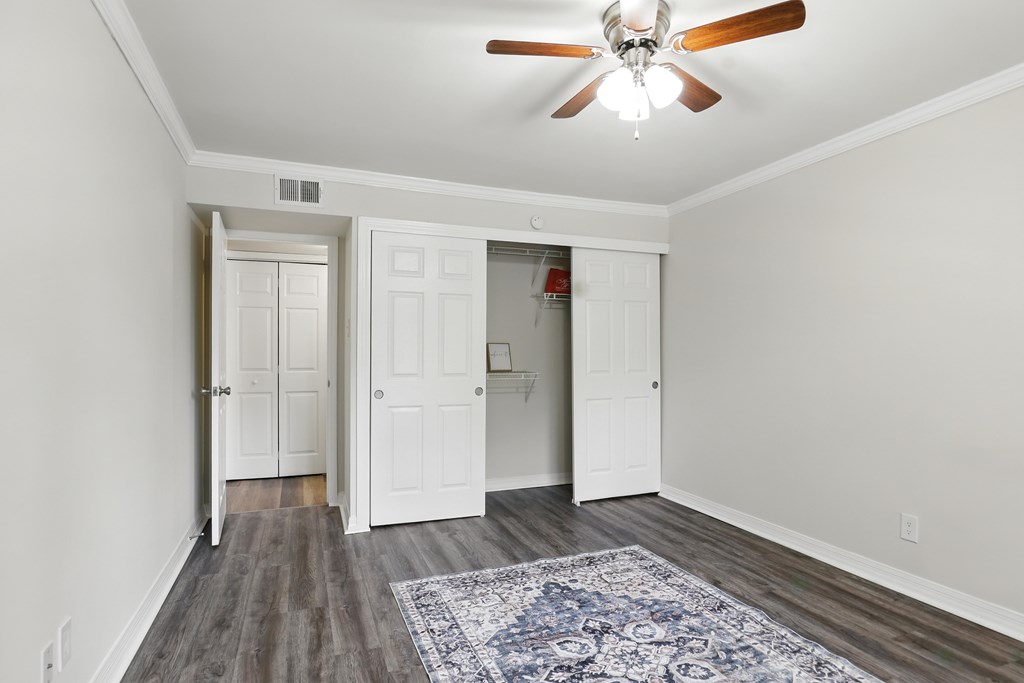 A room with a ceiling fan and a rug on the floor.