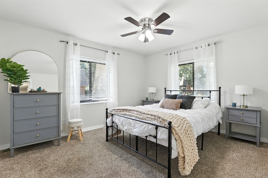 A bedroom with a bed, dresser, and window.