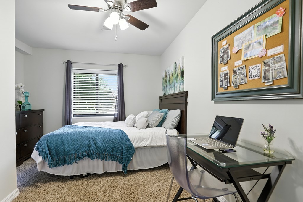 A bedroom with a bed, desk, and chair.
