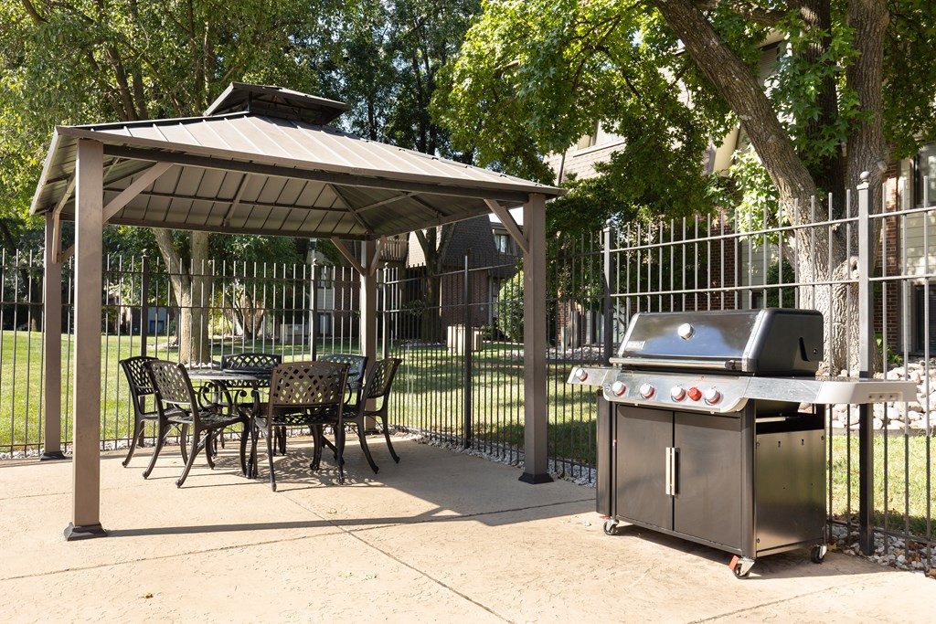 A patio with a grill and a table under a roof.
