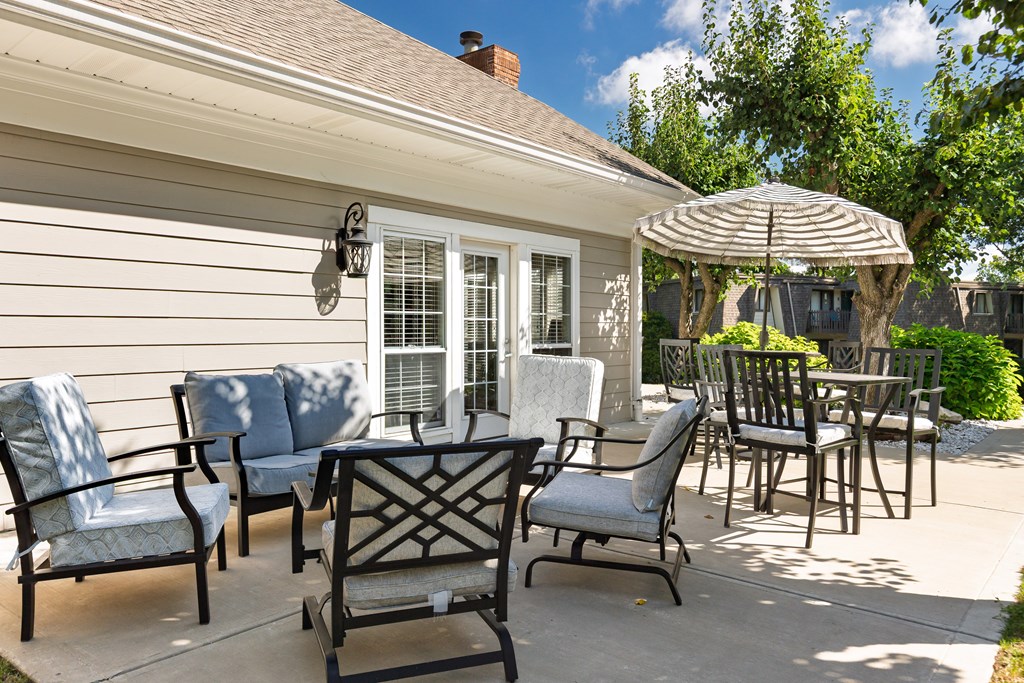 A patio with a table, chairs and an umbrella.