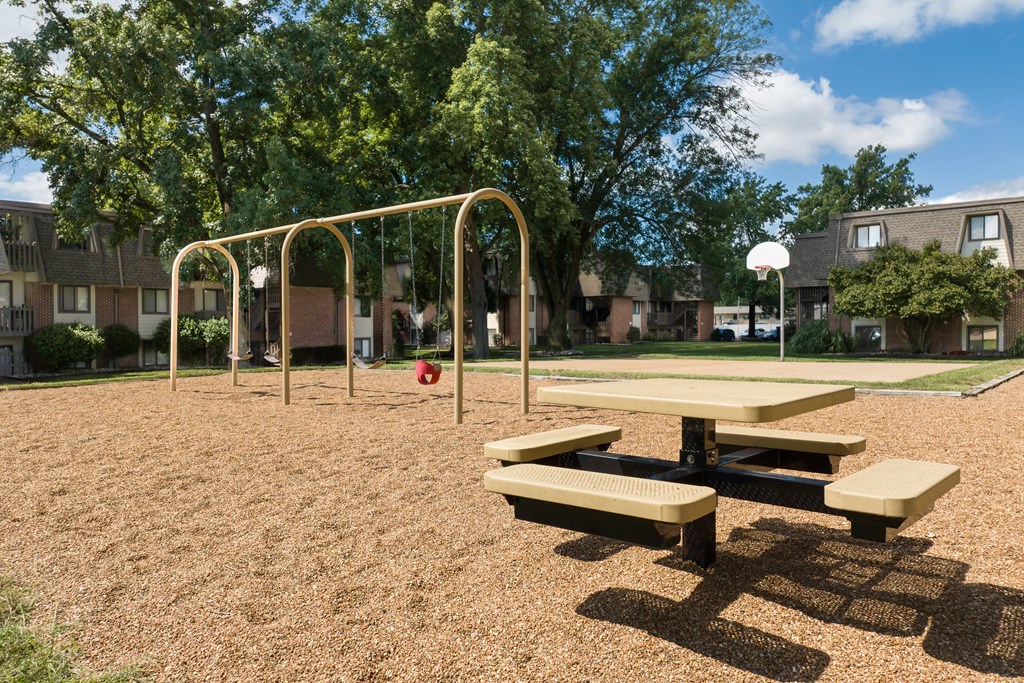 A playground with a swing set and picnic table.