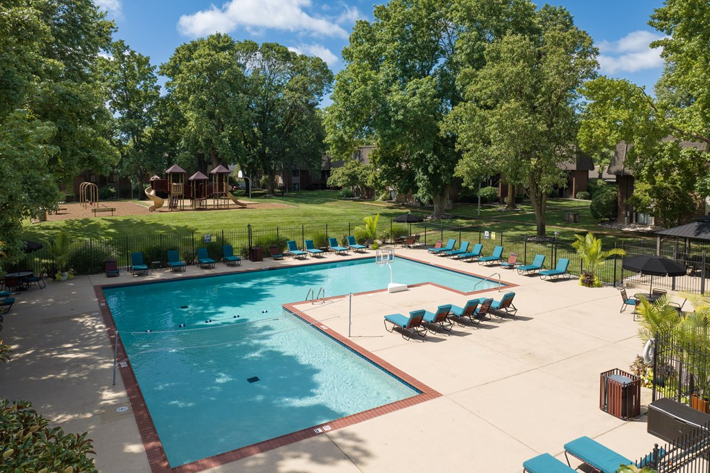 A large swimming pool surrounded by trees and lounge chairs.