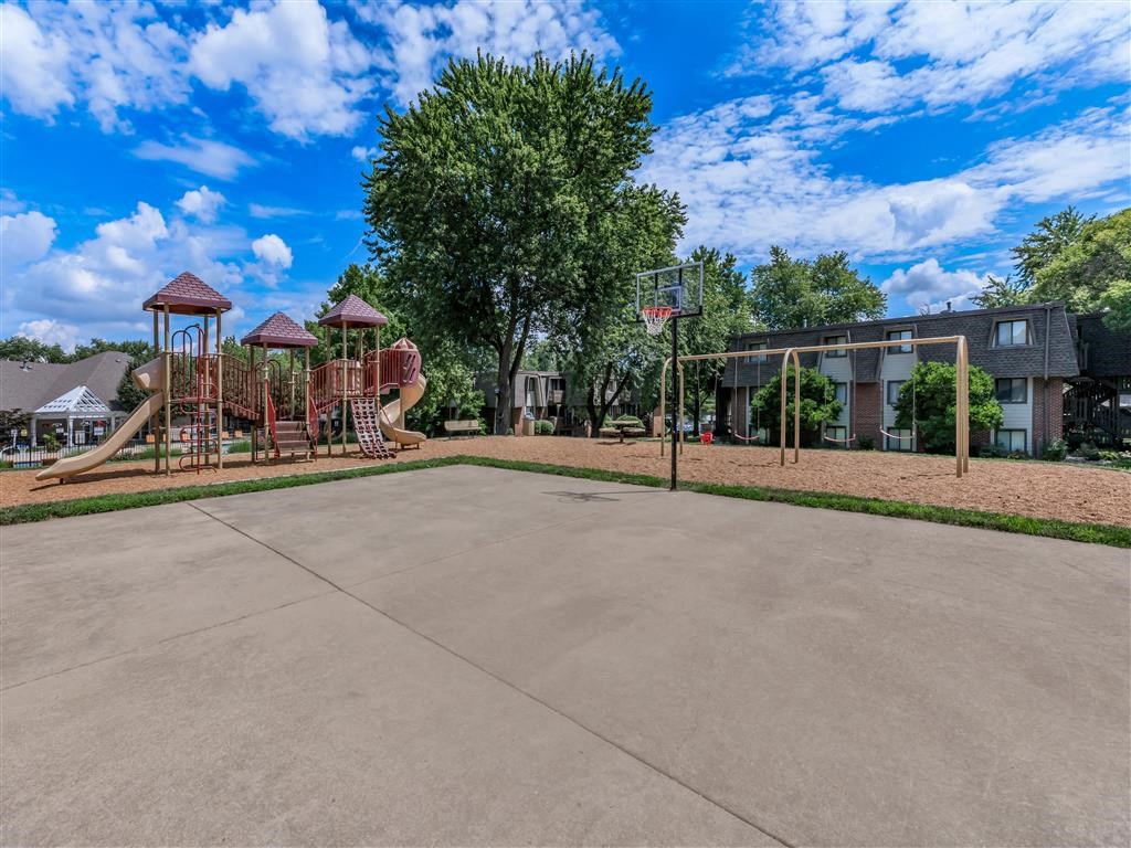 a basketball court with a playground and a building in the background