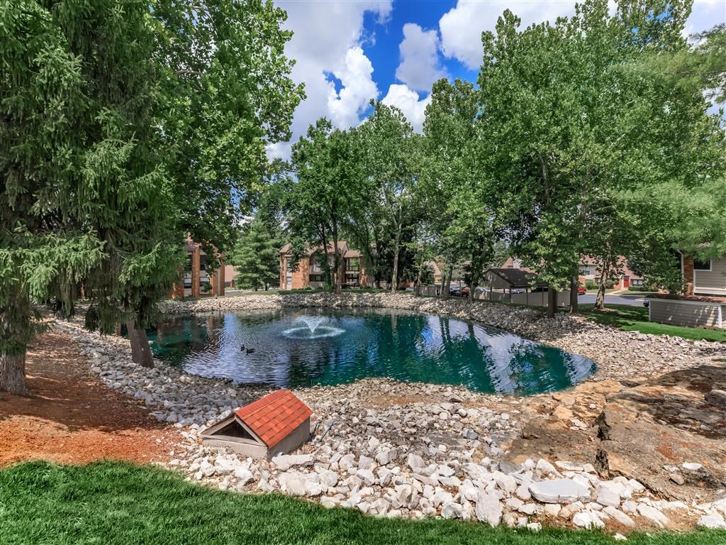 a pond with trees and a building in the background
