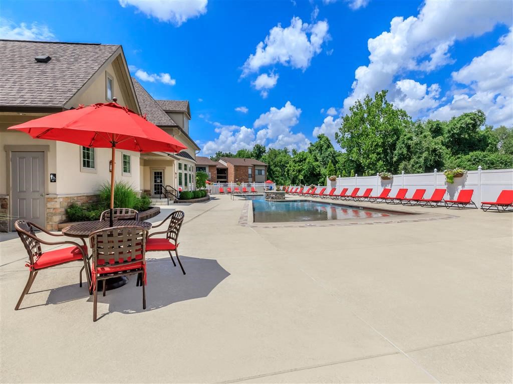 a swimming pool with a table and chairs next to a house