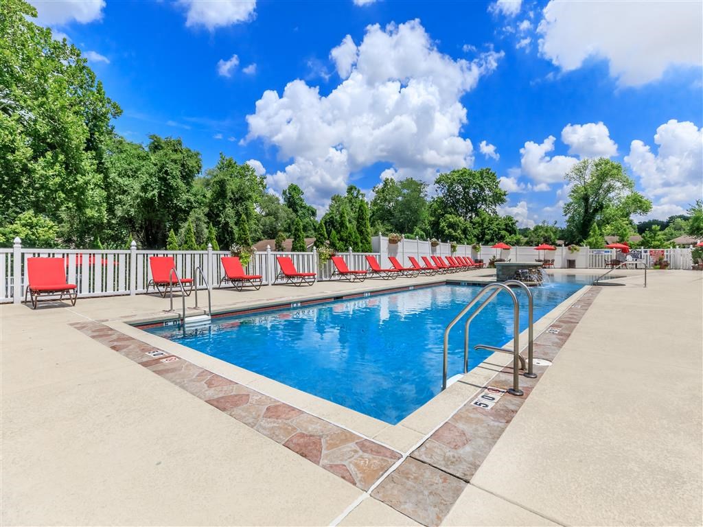 a swimming pool with red chairs around it