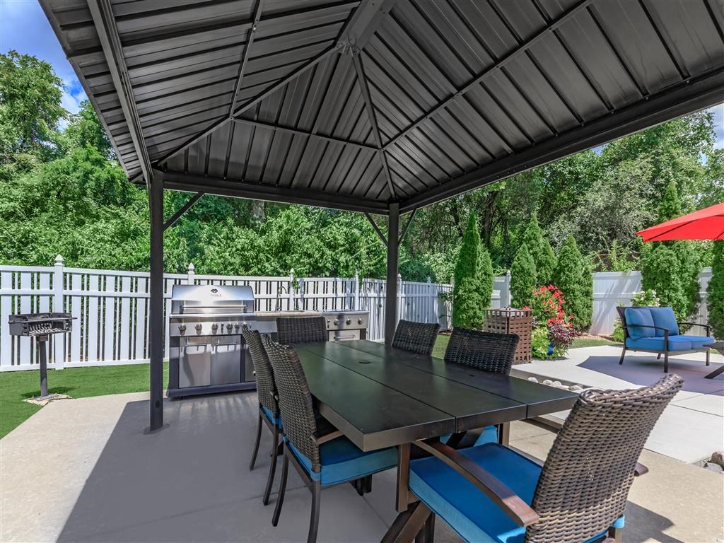 a patio with a table and chairs under a black gazebo