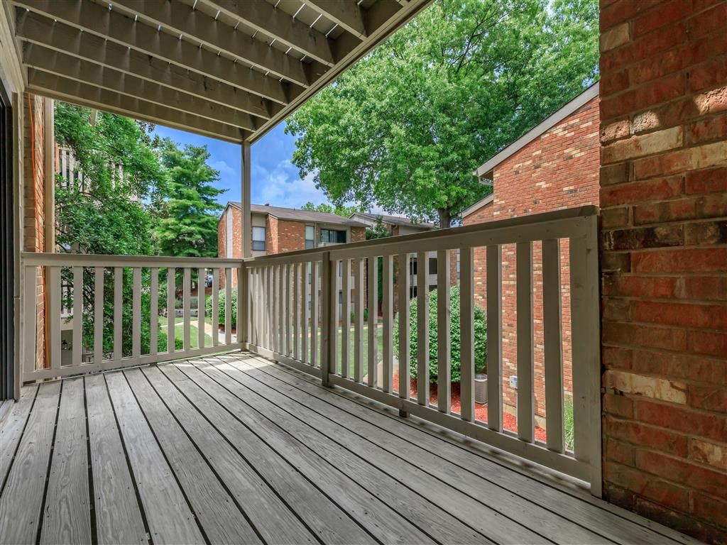the deck of a home with a brick wall and wooden railing