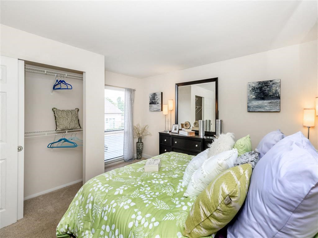 a bedroom with a green and white bed and a closet