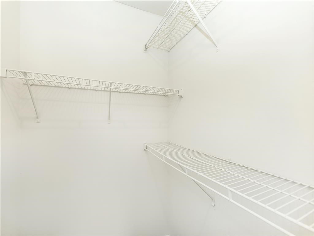 a walk in closet with white walls and shelves
